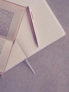 Creative flatlay featuring an open book, notebook, and pen on a textured surface.
